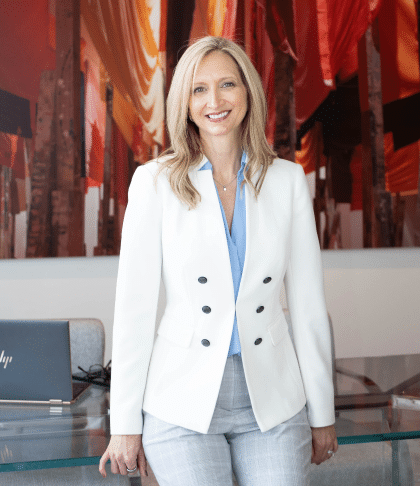 Johnda Denison leaning on office desk
