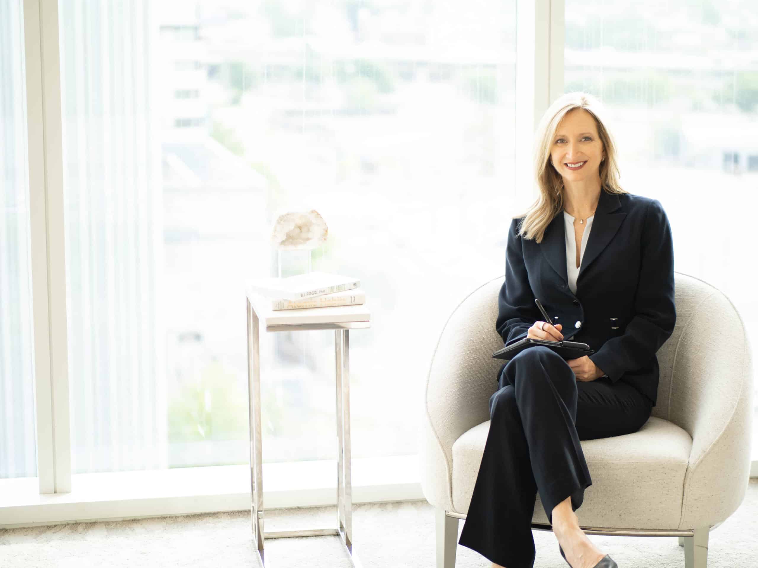 Johnda Denison in black suit sitting in chair
